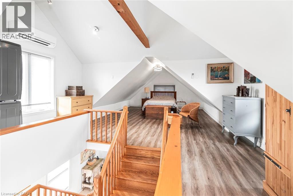 Bedroom with wood finished floors, vaulted ceiling with beams, and stacked washer / dryer - 57 New Street, Hamilton, ON - Indoor Photo Showing Other Room