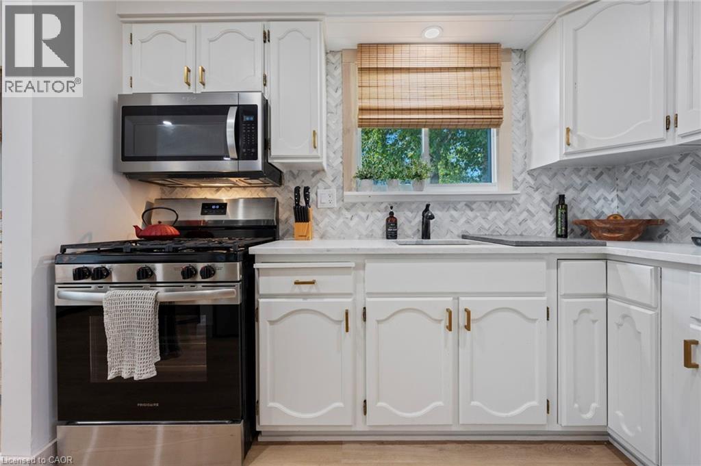 Kitchen with appliances with stainless steel finishes, white cabinets, light countertops, and decorative backsplash - 181 Cedar Drive, Turkey Point, ON - Indoor Photo Showing Kitchen