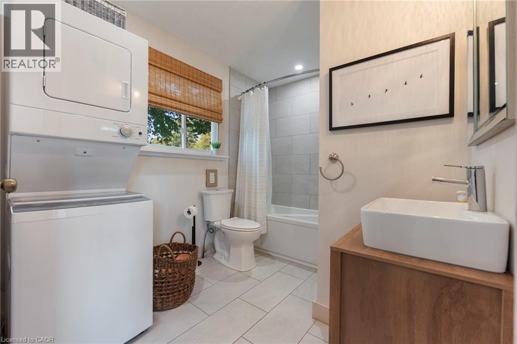 Full bath featuring stacked washer and clothes dryer, shower / bath combo with shower curtain, tile patterned flooring, and vanity - 181 Cedar Drive, Turkey Point, ON - Indoor