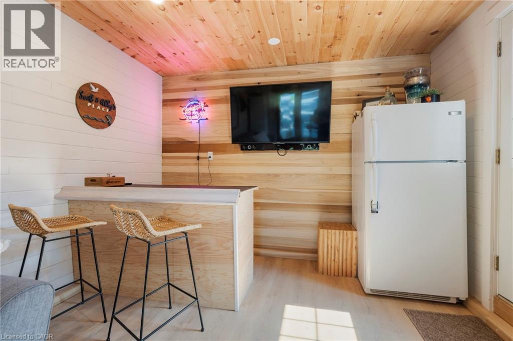Bar area with freestanding refrigerator, wood walls, wooden ceiling, and light wood finished floors - 181 Cedar Drive, Turkey Point, ON - Indoor