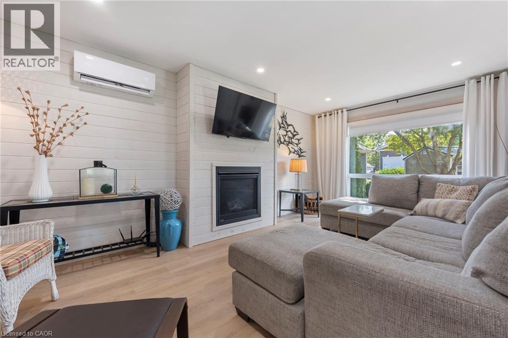 Living area featuring a wall mounted AC, wood finished floors, a fireplace, recessed lighting, and wood walls - 181 Cedar Drive, Turkey Point, ON - Indoor Photo Showing Living Room With Fireplace