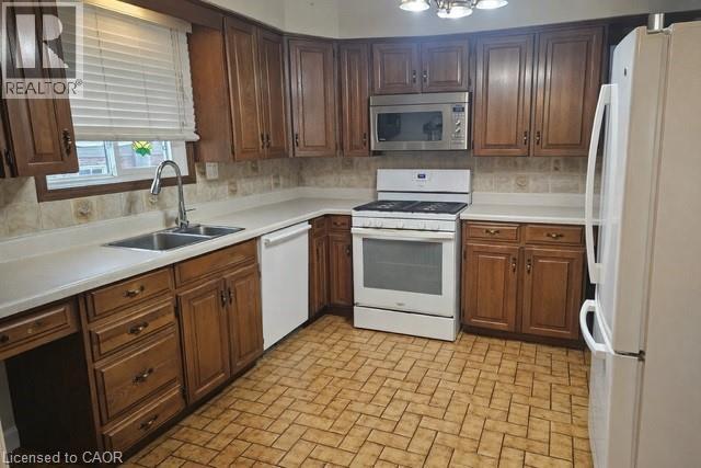 Kitchen with white appliances, light countertops, brick patterned floors, and tasteful backsplash - 226 Auburn Avenue, Hamilton, ON - Indoor Photo Showing Kitchen With Double Sink