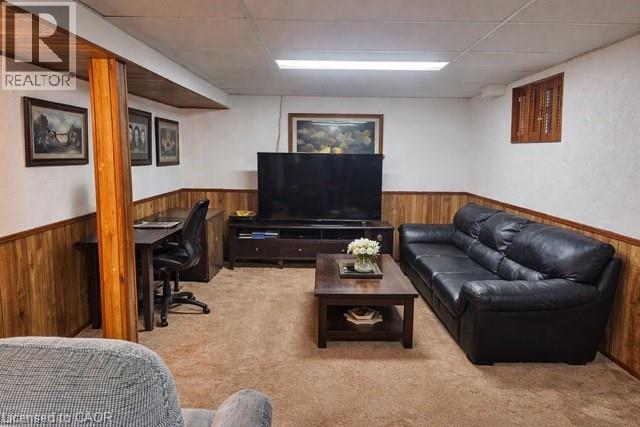 Living area with a drop ceiling, light carpet, a wainscoted wall, wooden walls, and a desk - 226 Auburn Avenue, Hamilton, ON - Indoor Photo Showing Basement