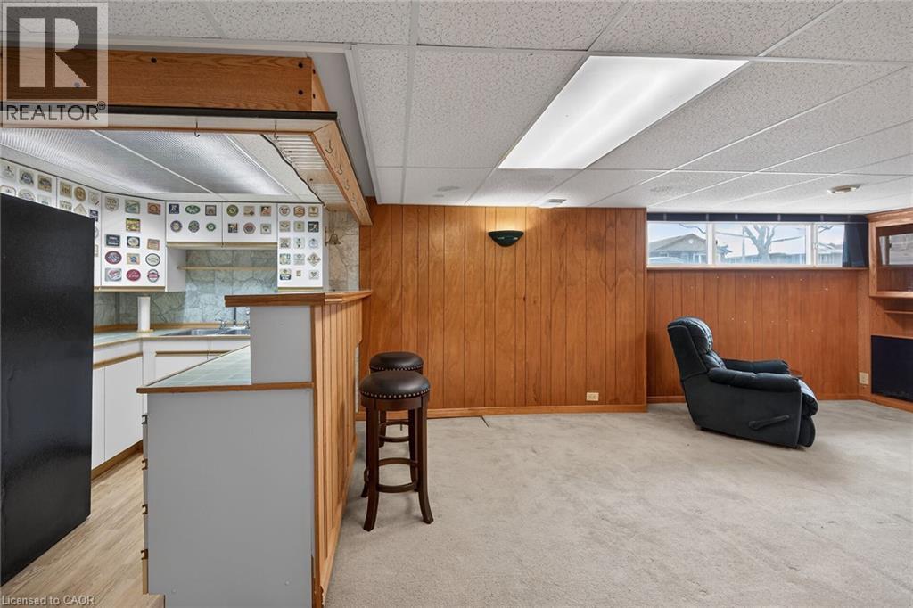 Bar area with freestanding refrigerator, white cabinetry, a paneled ceiling, light countertops, and wood walls - 19 Burfield Avenue, Hamilton, ON - Indoor Photo Showing Other Room