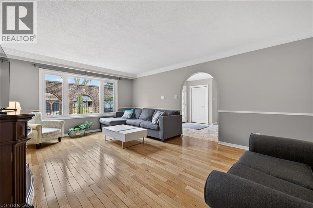 Living area featuring arched walkways, light wood finished floors, a textured ceiling, and ornamental molding - 22 Woodside Drive, Hamilton, ON - Indoor Photo Showing Living Room