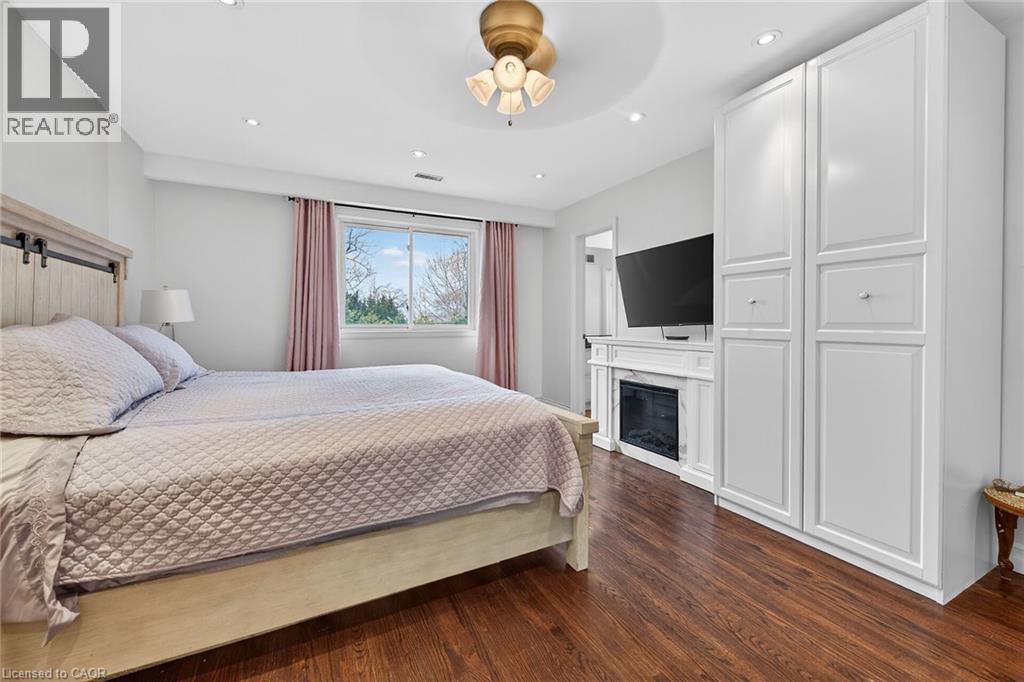Bedroom with dark wood-type flooring, a glass covered fireplace, and recessed lighting - 22 Woodside Drive, Hamilton, ON - Indoor Photo Showing Bedroom