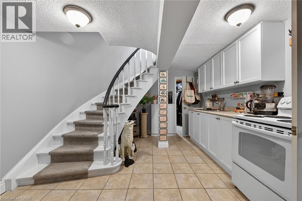 Kitchen with electric stove, white cabinets, light countertops, a textured ceiling, and light tile patterned floors - 22 Woodside Drive, Hamilton, ON - Indoor