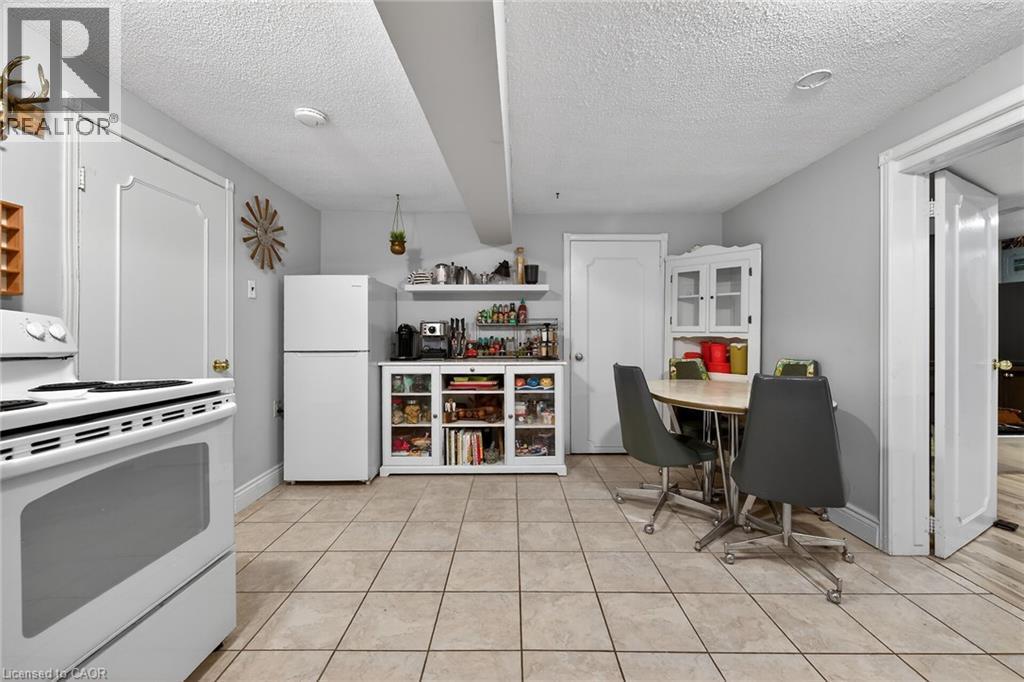 Kitchen with white appliances, a textured ceiling, white cabinets, open shelves, and light tile patterned floors - 22 Woodside Drive, Hamilton, ON - Indoor Photo Showing Kitchen