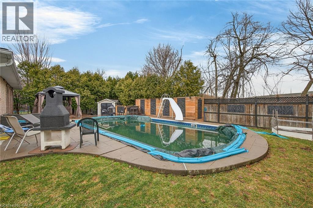 View of swimming pool with a water slide, a fenced backyard, and patio surround - 22 Woodside Drive, Hamilton, ON - Outdoor With In Ground Pool