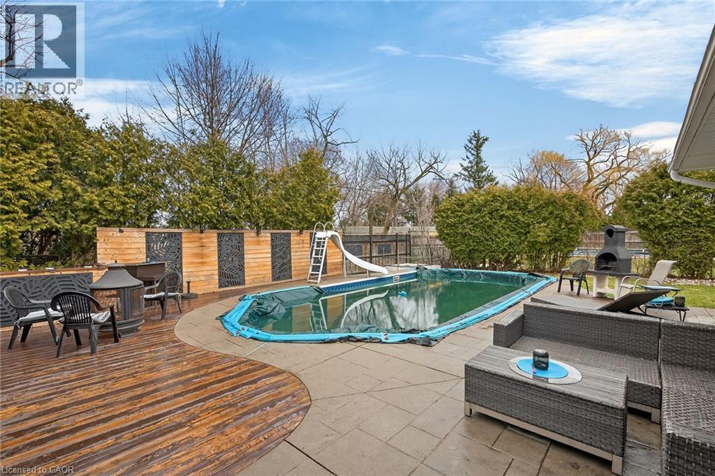 View of swimming pool featuring a water slide, a deck, an outdoor living space with a fireplace, and patio surround - 22 Woodside Drive, Hamilton, ON - Outdoor With In Ground Pool