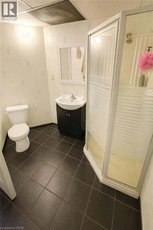 Bathroom featuring vanity, a shower stall, tile walls, and dark tile patterned floors - 988 Prosperity Court, London, ON - Indoor Photo Showing Bathroom