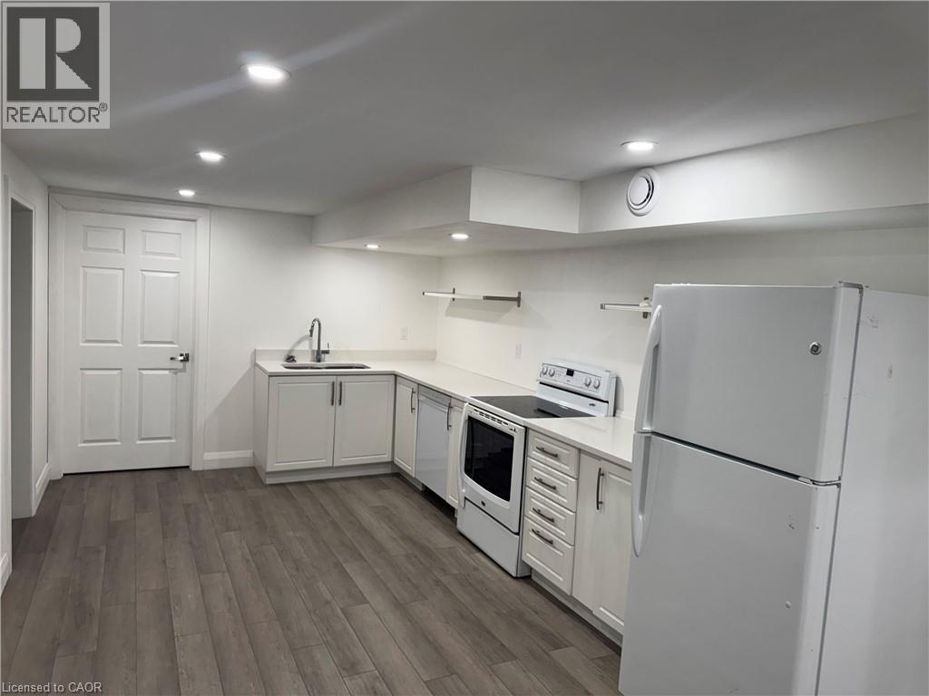 Kitchen with white appliances, light countertops, white cabinets, dark wood-style flooring, and recessed lighting - 18 Cyprus Drive Unit# Lower, Kitchener, ON - Indoor Photo Showing Kitchen