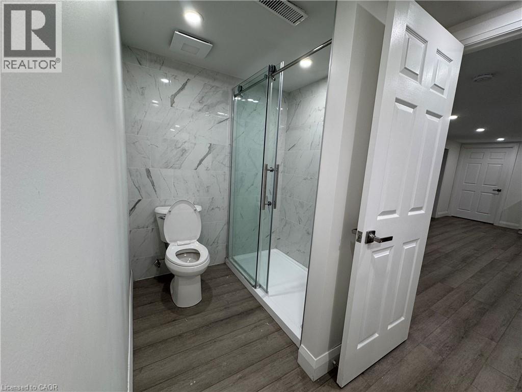 Bathroom with dark wood-style flooring and a marble finish shower - 18 Cyprus Drive Unit# Lower, Kitchener, ON - Indoor Photo Showing Bathroom