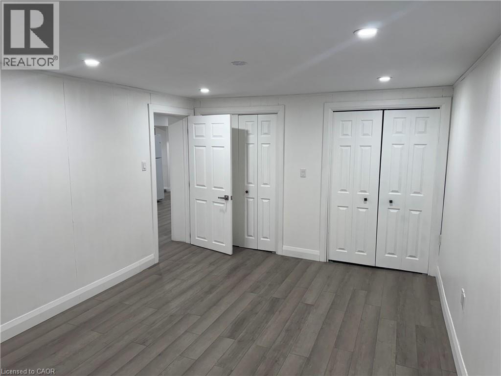 Unfurnished bedroom with multiple closets, dark wood-type flooring, and recessed lighting - 18 Cyprus Drive Unit# Lower, Kitchener, ON - Indoor Photo Showing Other Room