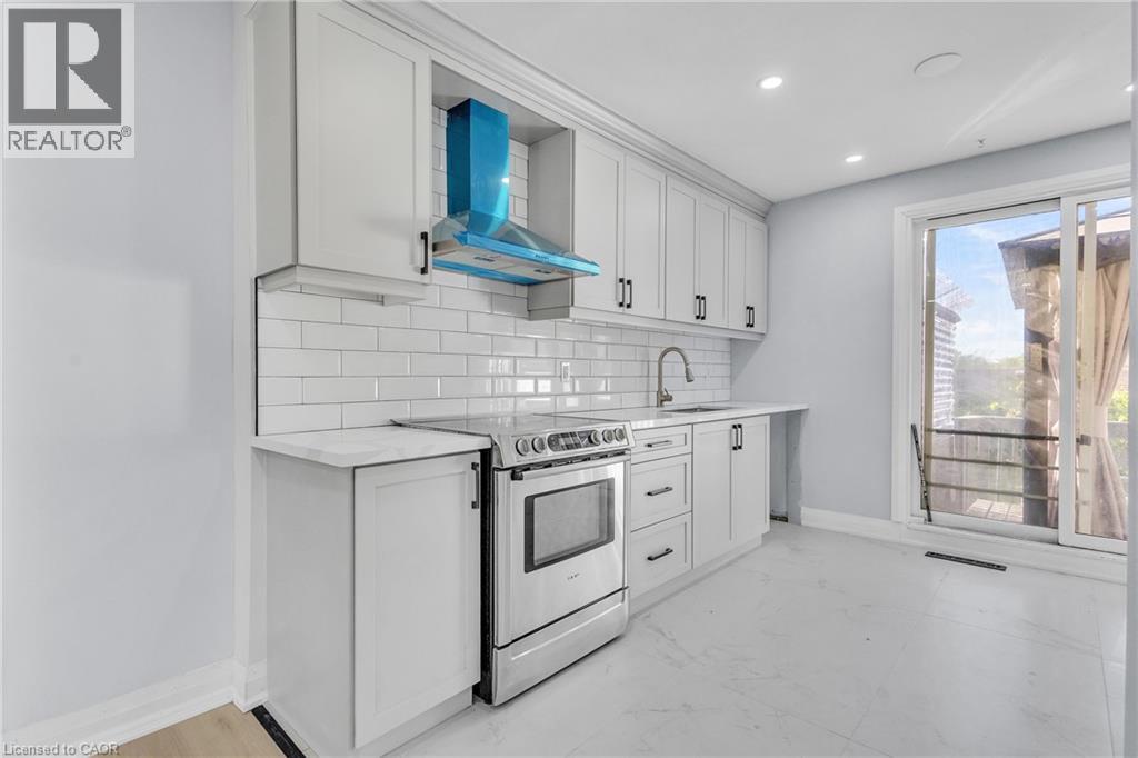 Kitchen featuring stainless steel range with electric stovetop, white cabinetry, tasteful backsplash, light stone counters, and recessed lighting - 84 Avalon Place, Kitchener, ON - Indoor Photo Showing Kitchen