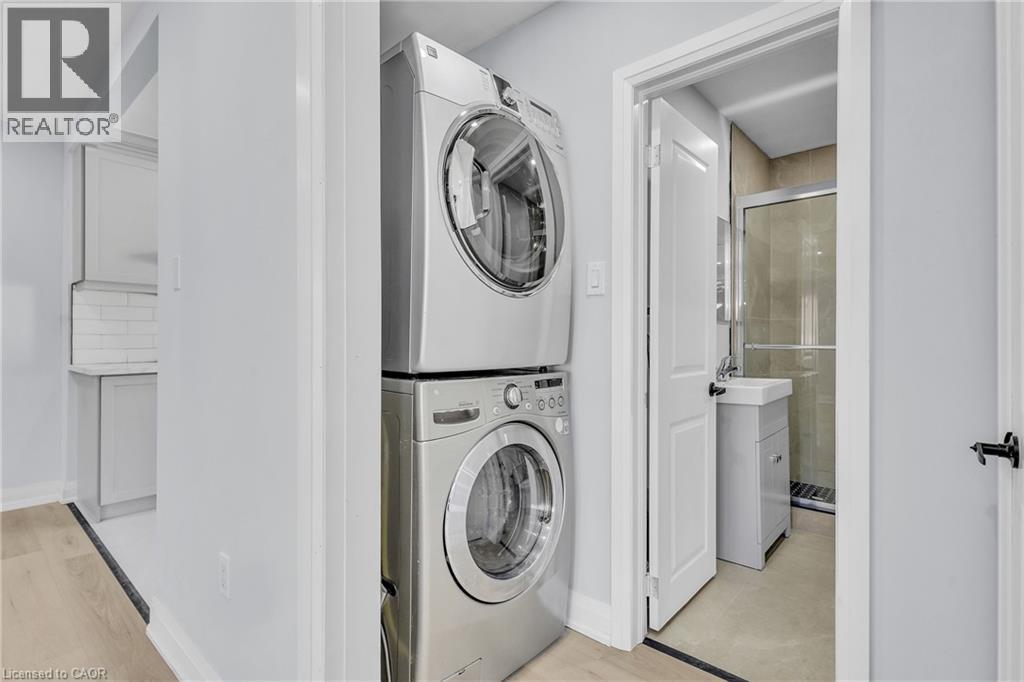 Laundry area with stacked washer / dryer and light wood-style flooring - 84 Avalon Place, Kitchener, ON - Indoor Photo Showing Laundry Room