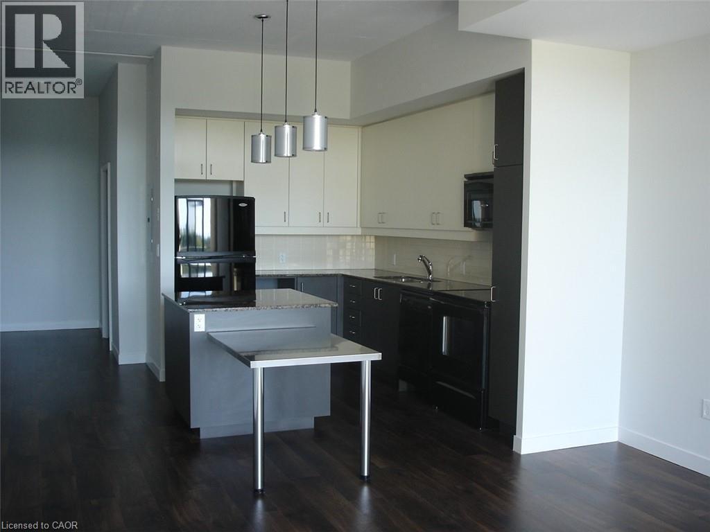 Two tone kitchen featuring tasteful backsplash, two tone cabinetry, black appliances, pendant lighting, and dark wood-style floors - 191 King Street S Unit# 712, Waterloo, ON - Indoor Photo Showing Kitchen