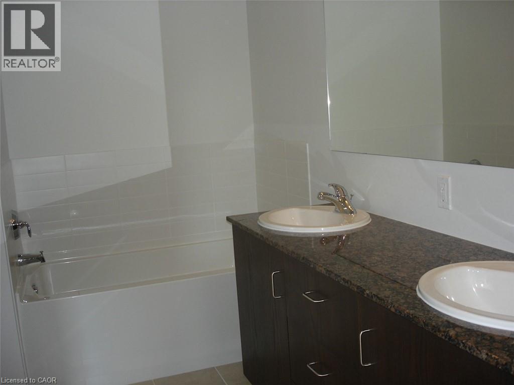 Full bath with double vanity, a garden tub, and light tile patterned floors - 191 King Street S Unit# 712, Waterloo, ON - Indoor Photo Showing Bathroom