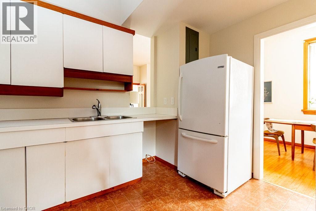 Kitchen featuring freestanding refrigerator, light countertops, white cabinetry, and light floors - 218 Bay Street S, Hamilton, ON