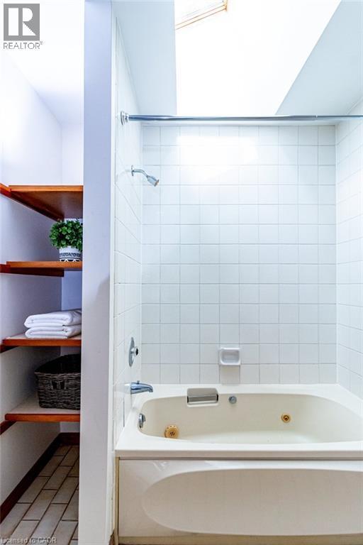 Bathroom featuring a combined bath / shower with jetted tub and baseboards - 218 Bay Street S, Hamilton, ON