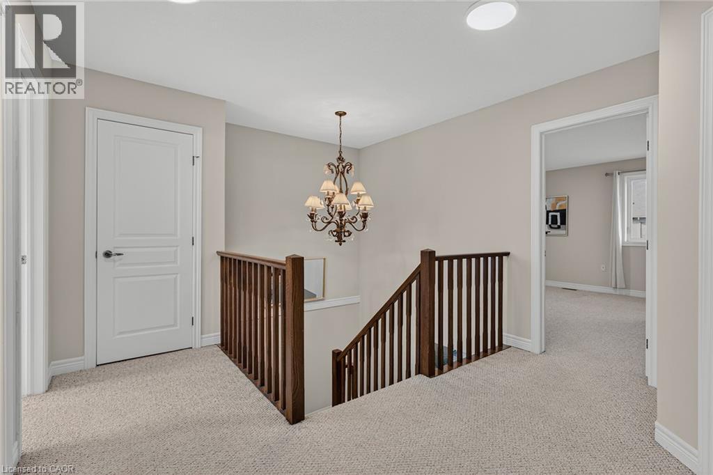 Hallway featuring light carpet, an upstairs landing, and hanging lights - 100 Garinger Crescent, Binbrook, ON - Indoor Photo Showing Other Room