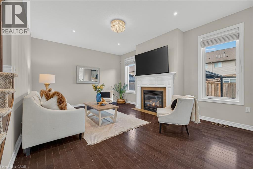 Living area with dark wood finished floors and a fireplace with flush hearth - 100 Garinger Crescent, Binbrook, ON - Indoor Photo Showing Living Room With Fireplace