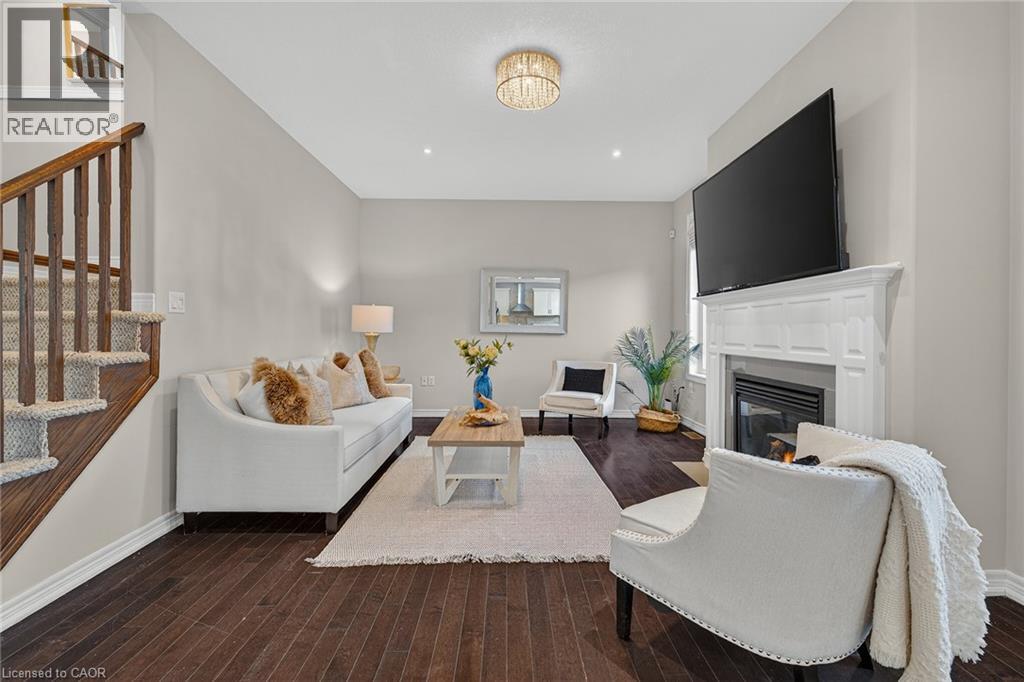 Living area with dark wood-style flooring and a fireplace with flush hearth - 100 Garinger Crescent, Binbrook, ON - Indoor Photo Showing Living Room With Fireplace