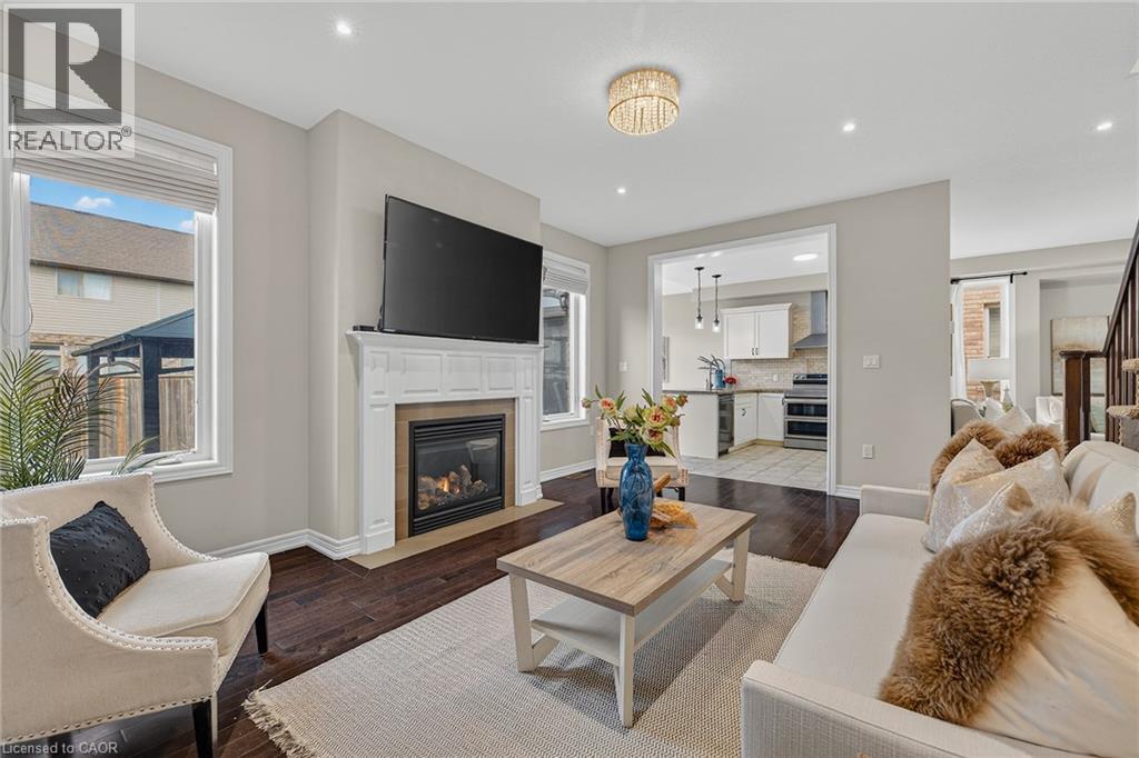 Living area with dark wood-style floors, a fireplace with flush hearth, recessed lighting, and a barn door - 100 Garinger Crescent, Binbrook, ON - Indoor Photo Showing Living Room With Fireplace