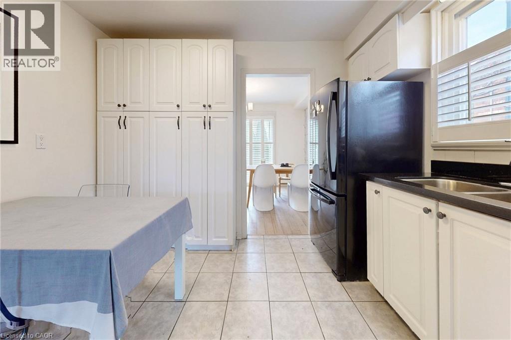 Kitchen featuring white cabinetry, freestanding refrigerator, and dark stone countertops - 62 Como Place, Hamilton, ON - Indoor Photo Showing Kitchen