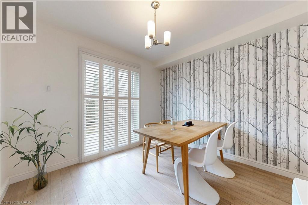 Dining space featuring an accent wall, wallpapered walls, light wood-style flooring, and a chandelier - 62 Como Place, Hamilton, ON - Indoor Photo Showing Dining Room