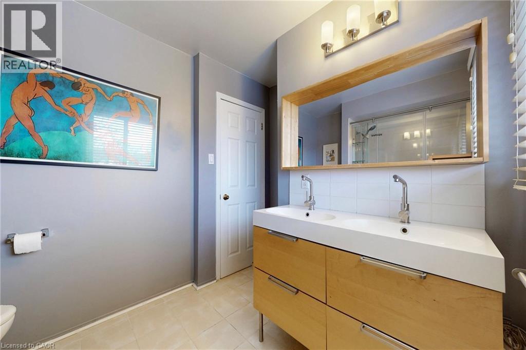 Bathroom with double vanity, tasteful backsplash, light tile patterned flooring, and an enclosed shower - 62 Como Place, Hamilton, ON - Indoor Photo Showing Bathroom