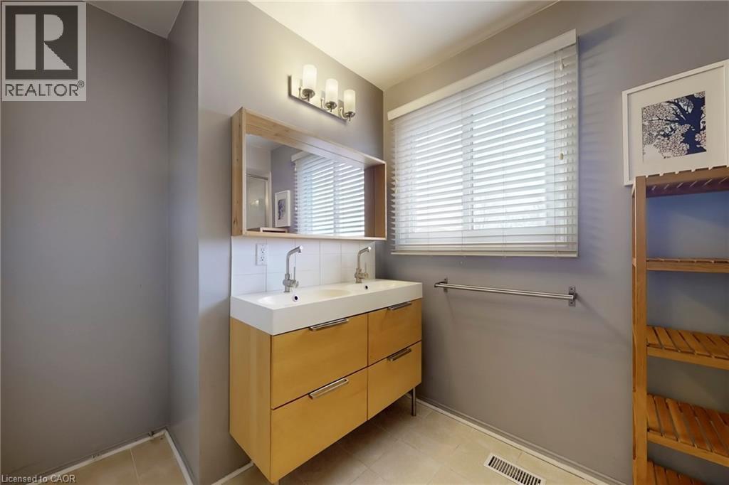 Bathroom featuring double vanity, backsplash, and light tile patterned floors - 62 Como Place, Hamilton, ON - Indoor Photo Showing Bathroom