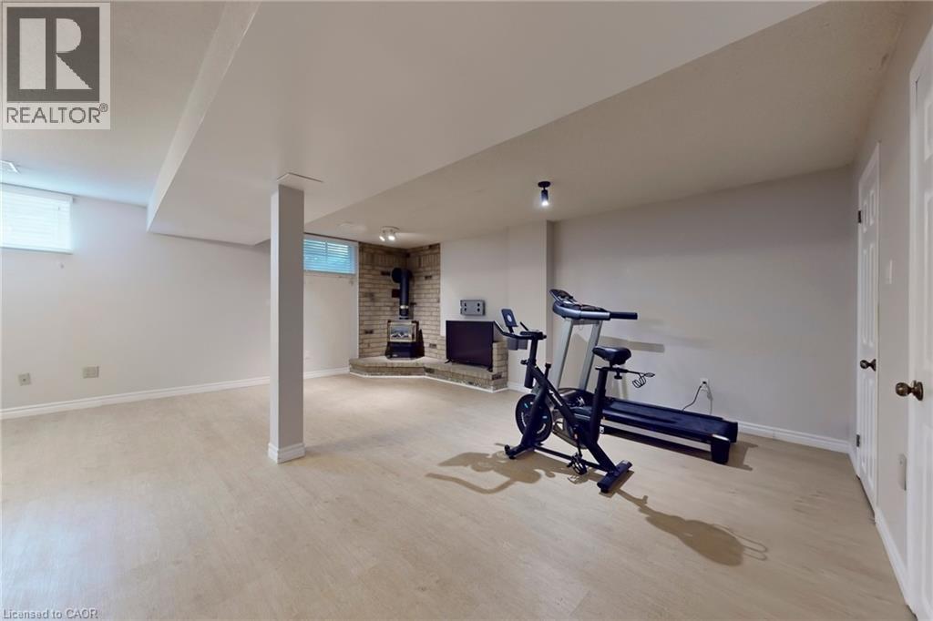 Workout room with a wood stove, light wood-style floors, and healthy amount of natural light - 62 Como Place, Hamilton, ON - Indoor Photo Showing Gym Room