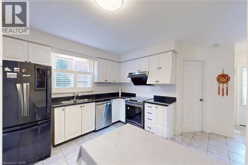 Kitchen with stainless steel appliances, white cabinetry, and dark countertops - 62 Como Place, Hamilton, ON - Indoor Photo Showing Kitchen With Double Sink