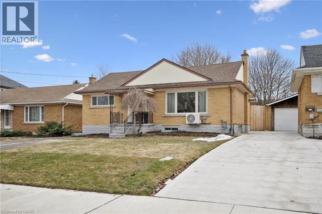 View of front of house featuring a chimney, brick siding, a front lawn, an outdoor structure, and a garage - 699 Frederick Street, Kitchener, ON - Outdoor With Facade