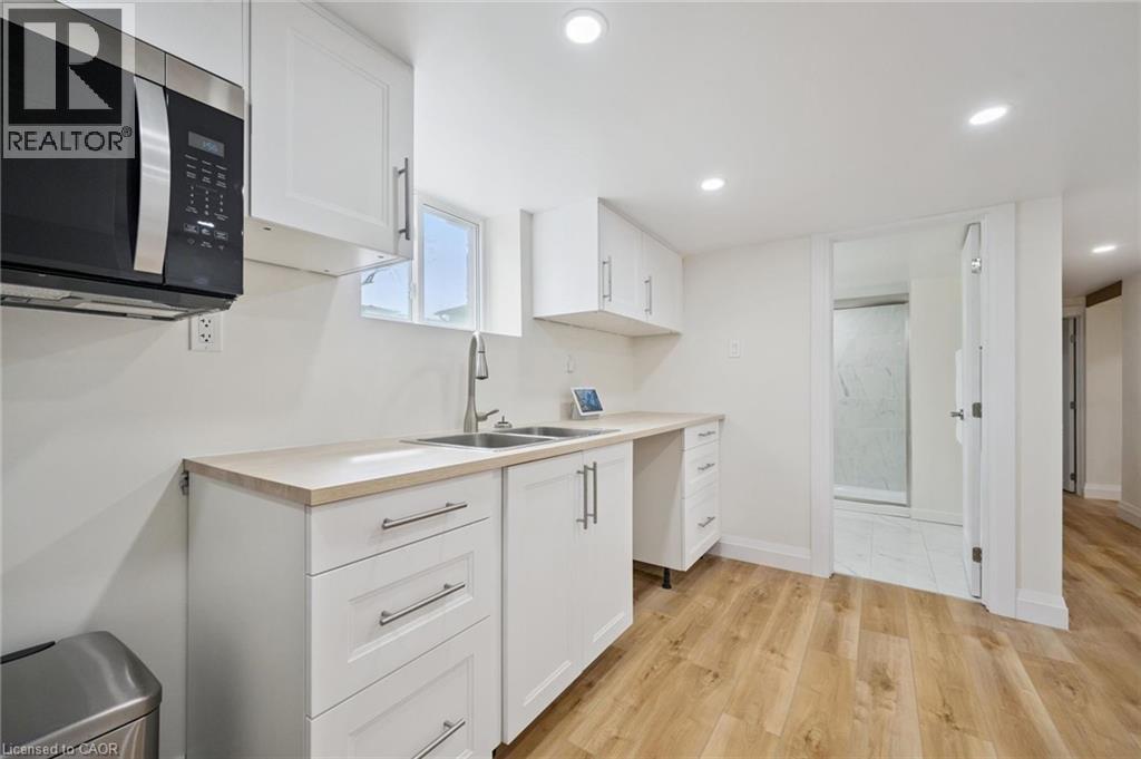 Kitchen with light countertops, white cabinetry, light wood-type flooring, and recessed lighting - 699 Frederick Street, Kitchener, ON - Indoor Photo Showing Kitchen With Double Sink