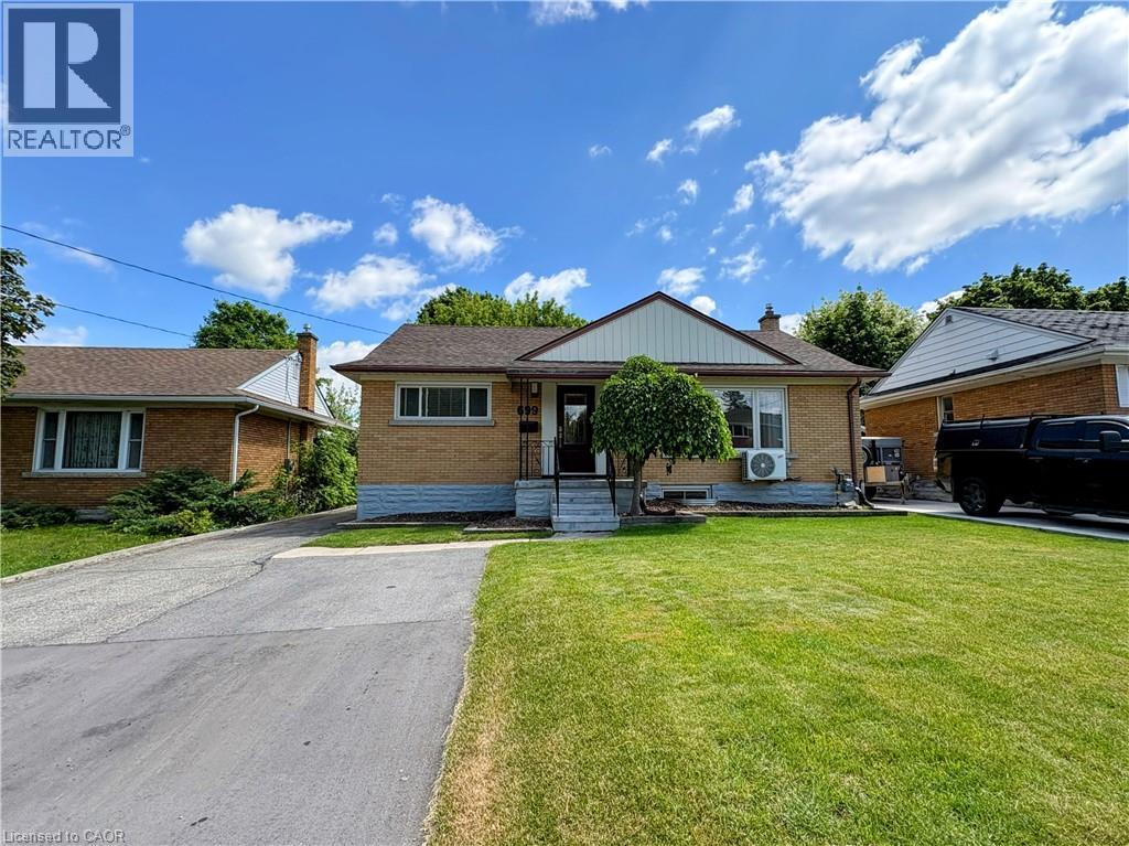 Traditional brick exterior with a pitched shingle roof, featuring a front porch with steps and a manicured lawn - 699 Frederick Street, Kitchener, ON