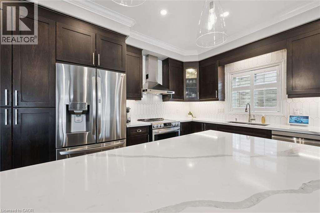 Kitchen featuring stainless steel appliances, glass fronted cabinets, light stone counters, dark wood finish cabinets, and ornamental molding - 469 Woodbine Avenue, Kitchener, ON - Indoor Photo Showing Kitchen With Stainless Steel Kitchen With Upgraded Kitchen