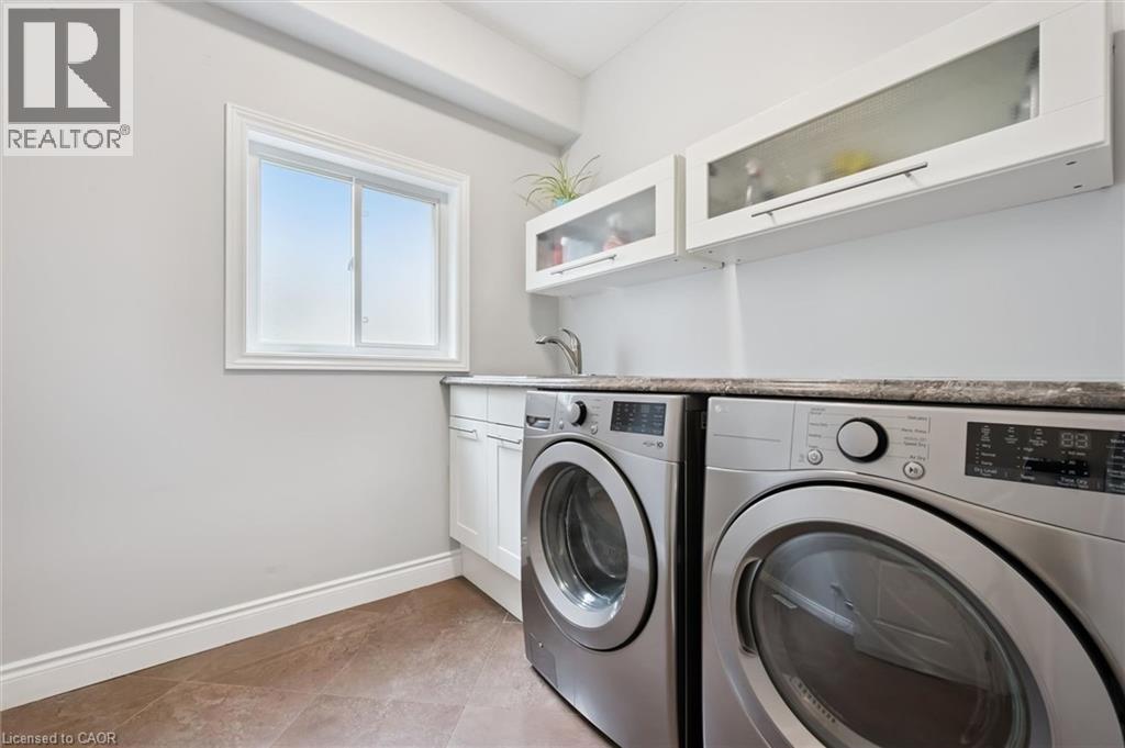 Laundry area featuring cabinet space, washer and clothes dryer, and light tile patterned flooring - 469 Woodbine Avenue, Kitchener, ON - Indoor Photo Showing Laundry Room