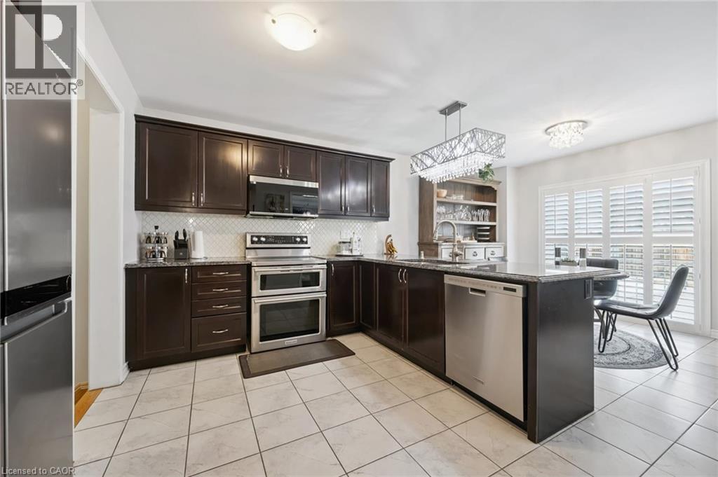Kitchen featuring a peninsula, dark wood finish cabinets, stainless steel appliances, dark stone counters, and pendant lighting - 38 Park Glen Street, Kitchener, ON - Indoor Photo Showing Kitchen With Stainless Steel Kitchen With Upgraded Kitchen