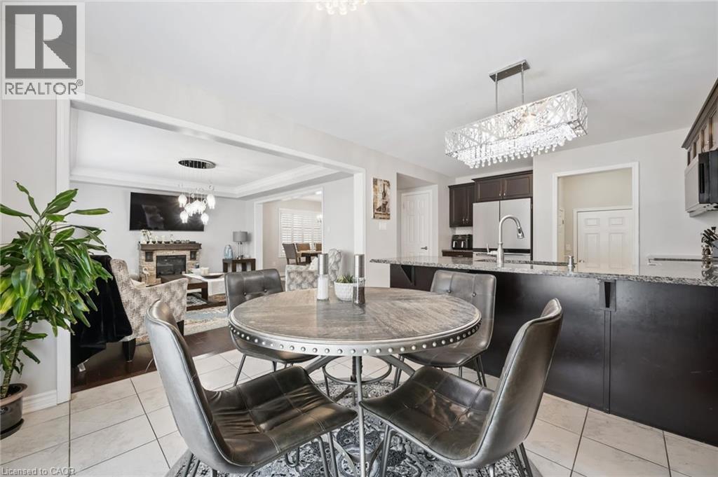 Dining space with hanging lights, a glass covered fireplace, light tile patterned flooring, and a raised ceiling - 38 Park Glen Street, Kitchener, ON - Indoor Photo Showing Dining Room With Fireplace