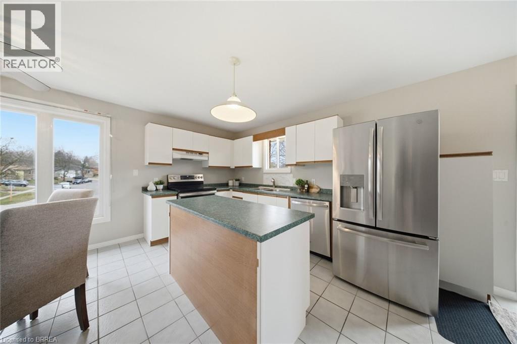 Kitchen featuring stainless steel appliances, a kitchen island, white cabinets, decorative light fixtures, and dark countertops - 7 Forest Drive, Paris, ON - Indoor Photo Showing Kitchen