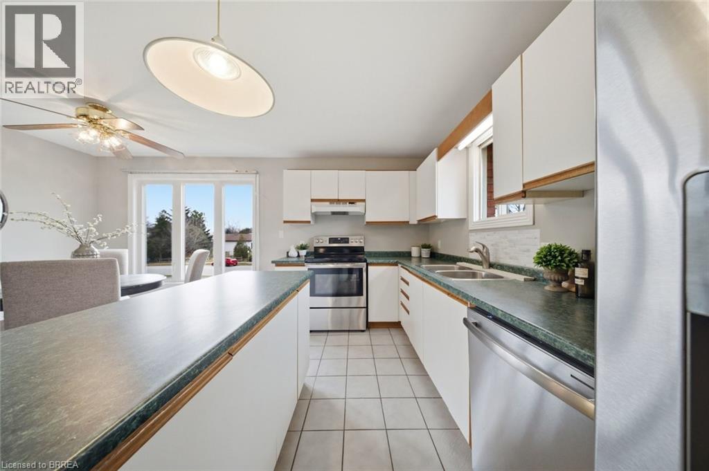 Kitchen with white cabinets, dark countertops, stainless steel appliances, and ceiling fan - 7 Forest Drive, Paris, ON - Indoor Photo Showing Kitchen With Double Sink