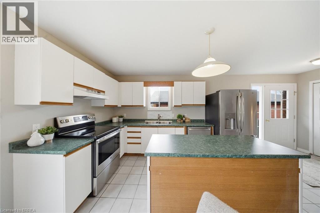 Kitchen featuring stainless steel appliances, a kitchen island, dark countertops, white cabinets, and pendant lighting - 7 Forest Drive, Paris, ON - Indoor Photo Showing Kitchen