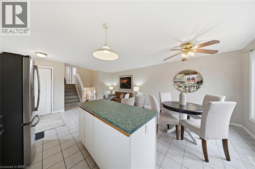Kitchen featuring freestanding refrigerator, white cabinets, dark countertops, hanging light fixtures, and light tile patterned floors - 7 Forest Drive, Paris, ON - Indoor Photo Showing Dining Room