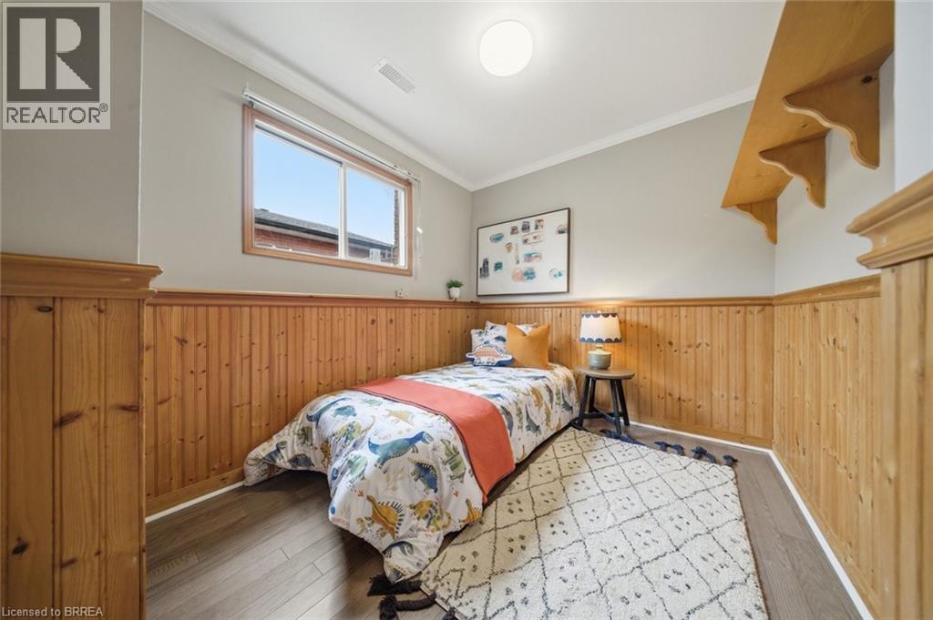 Bedroom featuring ornamental molding, wooden walls, wood-type flooring, and a wainscoted wall - 7 Forest Drive, Paris, ON - Indoor Photo Showing Bedroom