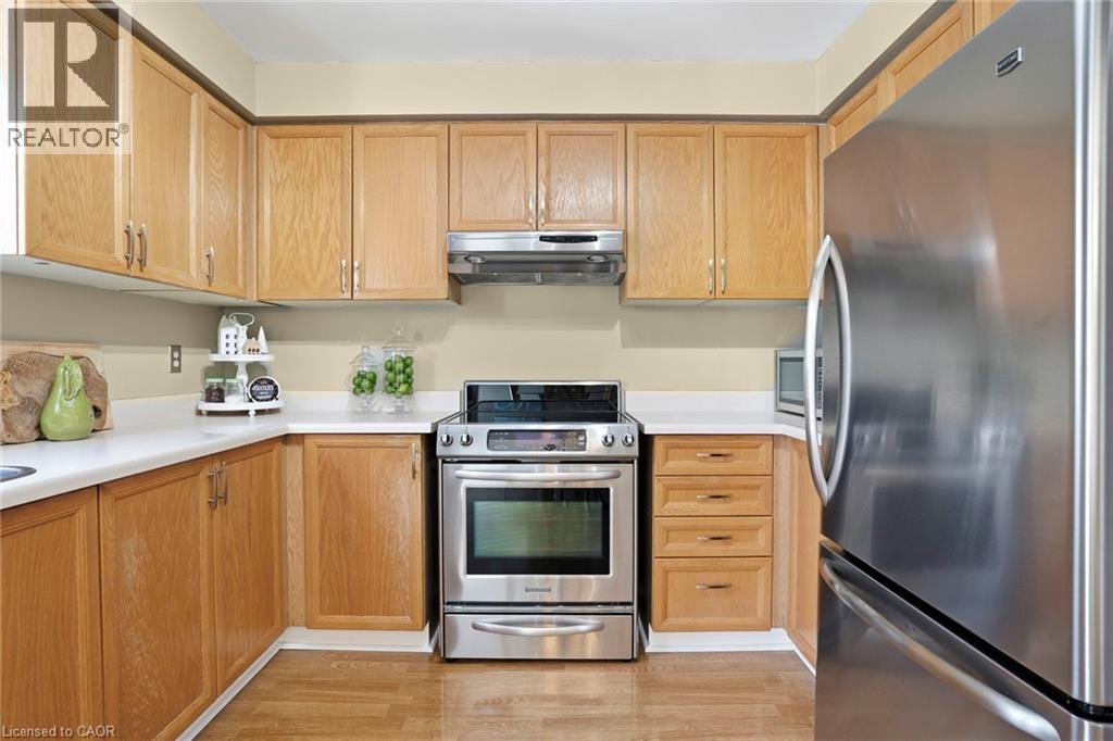 Kitchen with stainless steel appliances, light countertops, and light wood finished floors - 18 Webster Way, Georgetown, ON - Indoor Photo Showing Kitchen