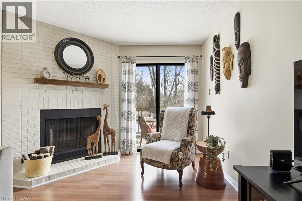 Living area with wood finished floors, a brick fireplace, and a textured ceiling - 18 Webster Way, Georgetown, ON - Indoor Photo Showing Living Room With Fireplace