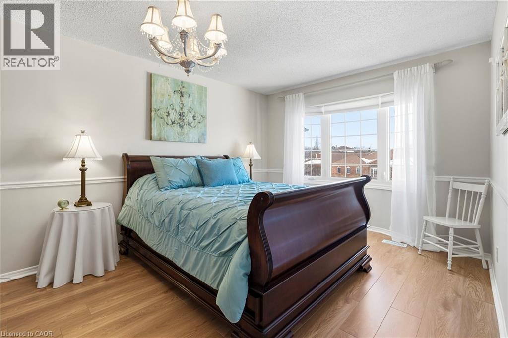 Bedroom featuring light wood-type flooring, hanging lights, and a textured ceiling - 18 Webster Way, Georgetown, ON - Indoor Photo Showing Bedroom