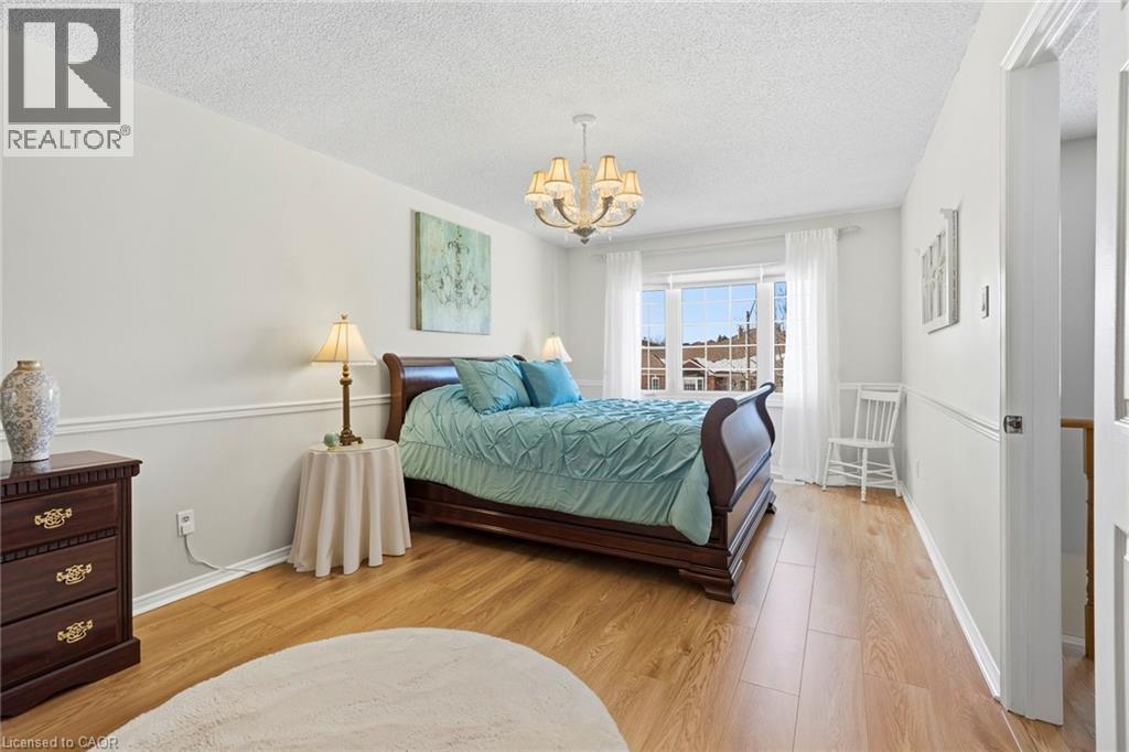 Bedroom featuring light wood-style floors, suspended lighting, and a textured ceiling - 18 Webster Way, Georgetown, ON - Indoor Photo Showing Bedroom